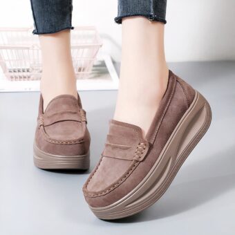 Woman wearing brown loafers with platform. Only her ankles are visible.