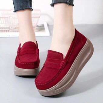 Photo of a pair of red wedge loafers worn by a woman in jeans on a gray floor