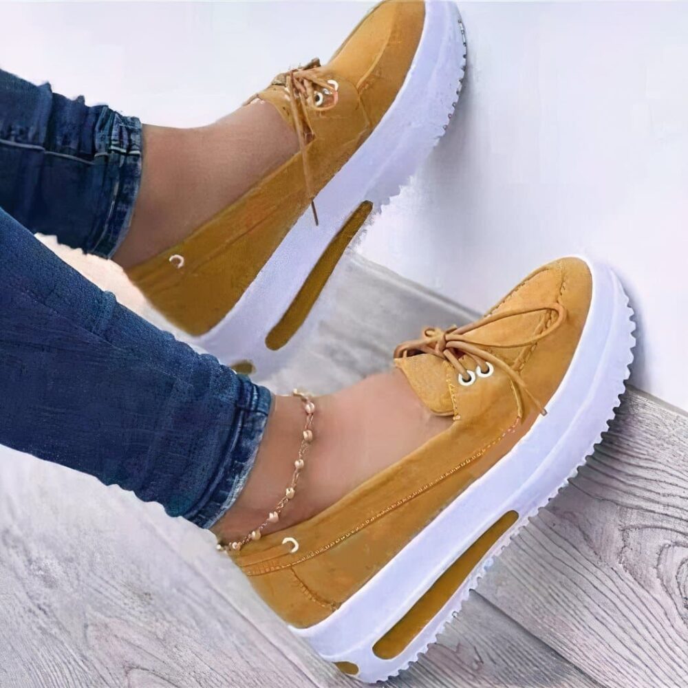 Photo of a pair of yellow platform loafers worn by a woman in jeans, on a parquet floor and white wall