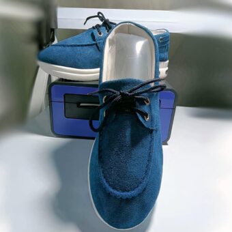 Photo of a pair of blue platform loafers on a white covering and set on a blue object