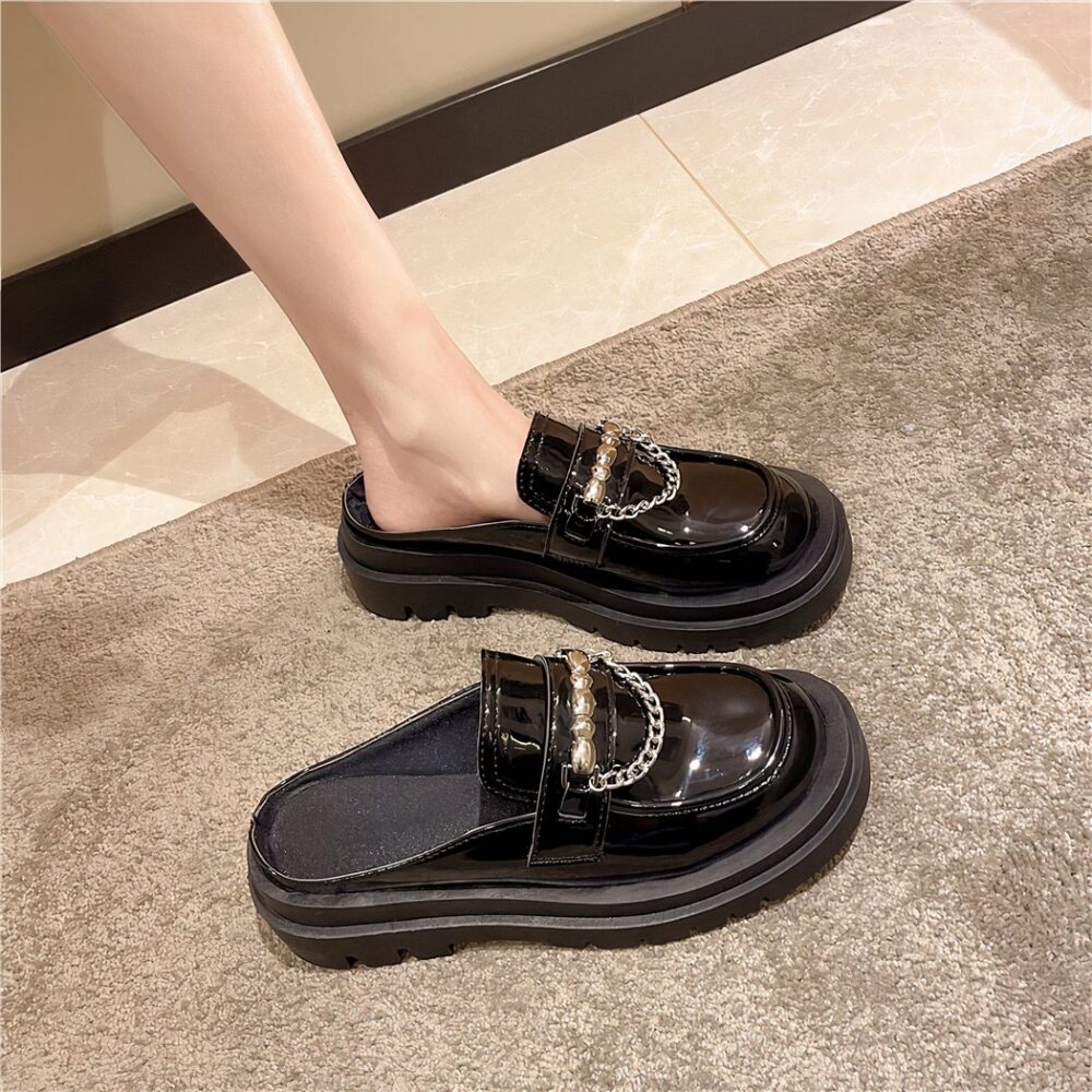 Photo of a pair of black platform loafers worn by a woman on a gray carpet