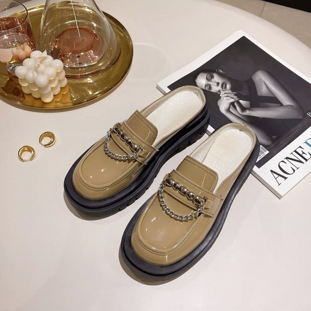 Shiny beige loafers on a floor with magazines.
