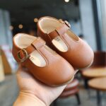 small moccasin for girl in brown faux leather worn by adult hand