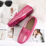 Photo of a pair of pink moccasins on newspapers, a pink plaid and sunglasses