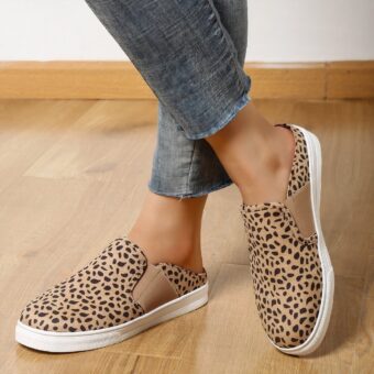 denim legs with exposed ankles wearing beige leopard print loafers with white platform on a beige parquet floor.