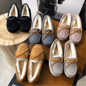Photo of several pairs of lined suede moccasins in different colors on a wooden cabinet.