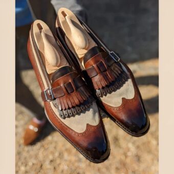 A pair of semi-polished moccasins in smooth leather and brown and beige synthetic suede with two-tone bangs and a strap and buckle fastening at the top.