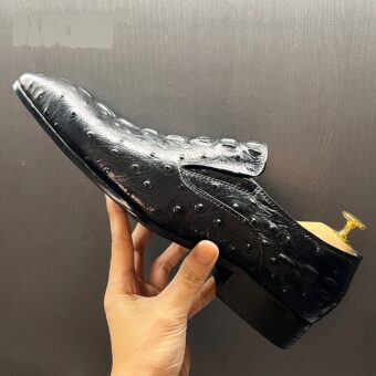 One person is holding a black crocodile-style moccasin with a shoe inside