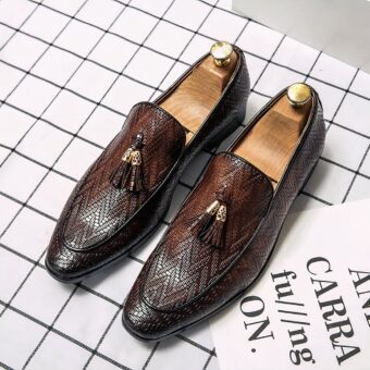 Leather loafers with zigzag patterns and decorative leather tassels with a gold metal yoke, dark pointed toes, on a white and black checkered ground.