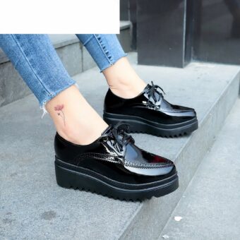 black patent women's wedge moccasin worn by a woman