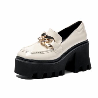 White moccasin with chunky black sole and gold buckles on a white background