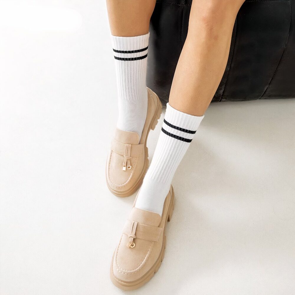 Woman's legs wearing high white socks and beige tassel loafers