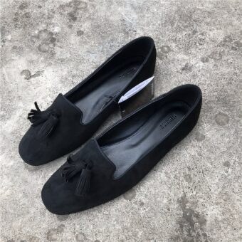 Pair of black suede-effect loafers on a grey concrete floor