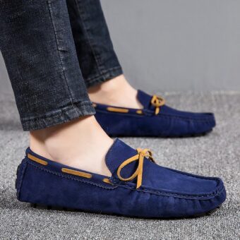 Feet of a man in profile wearing jeans and classic blue boat loafers