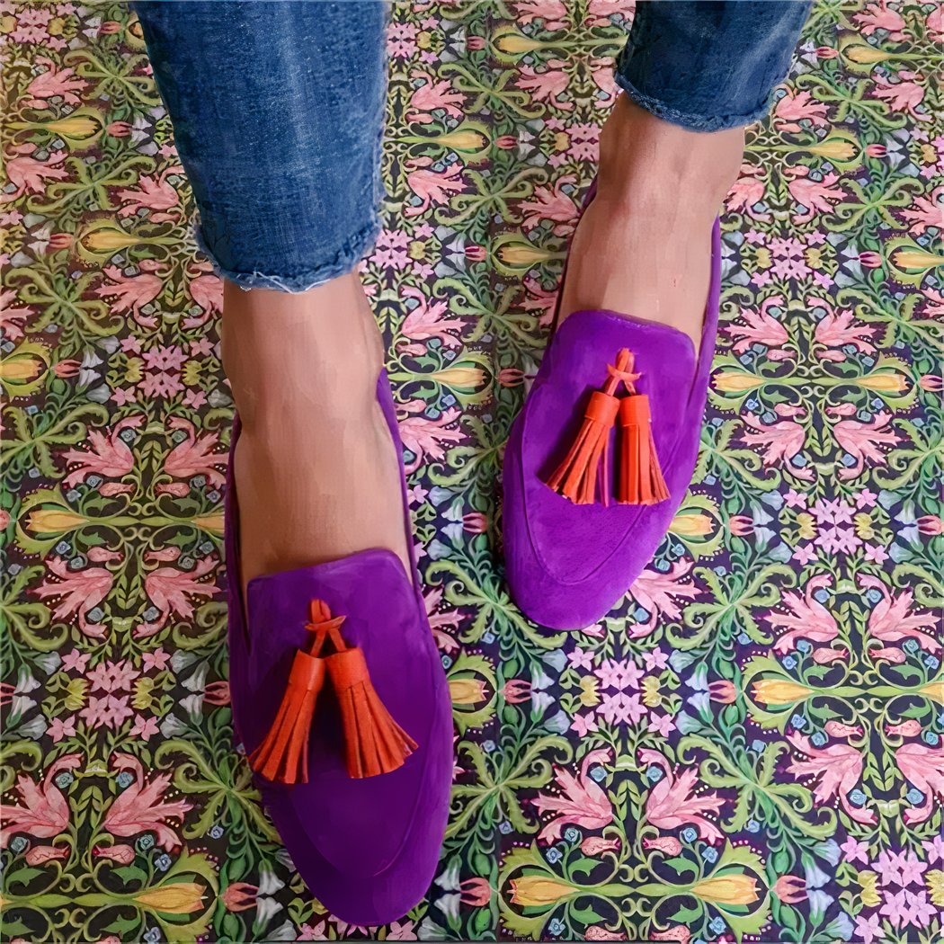woman in denim wearing purple pointed-toe loafers with orange tassels