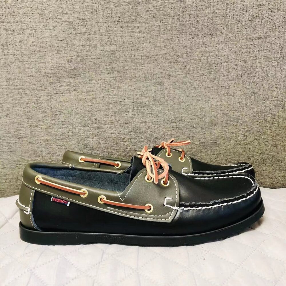 Pair of black and khaki boat moccasins on a white floor in profile