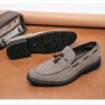 Two grey moccasins on brown tasselled parquet flooring