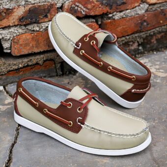 Beige boat moccasins on the floor against a brick wall