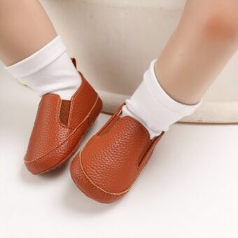 Baby wearing white socks and plain brown moccasins in synthetic leather