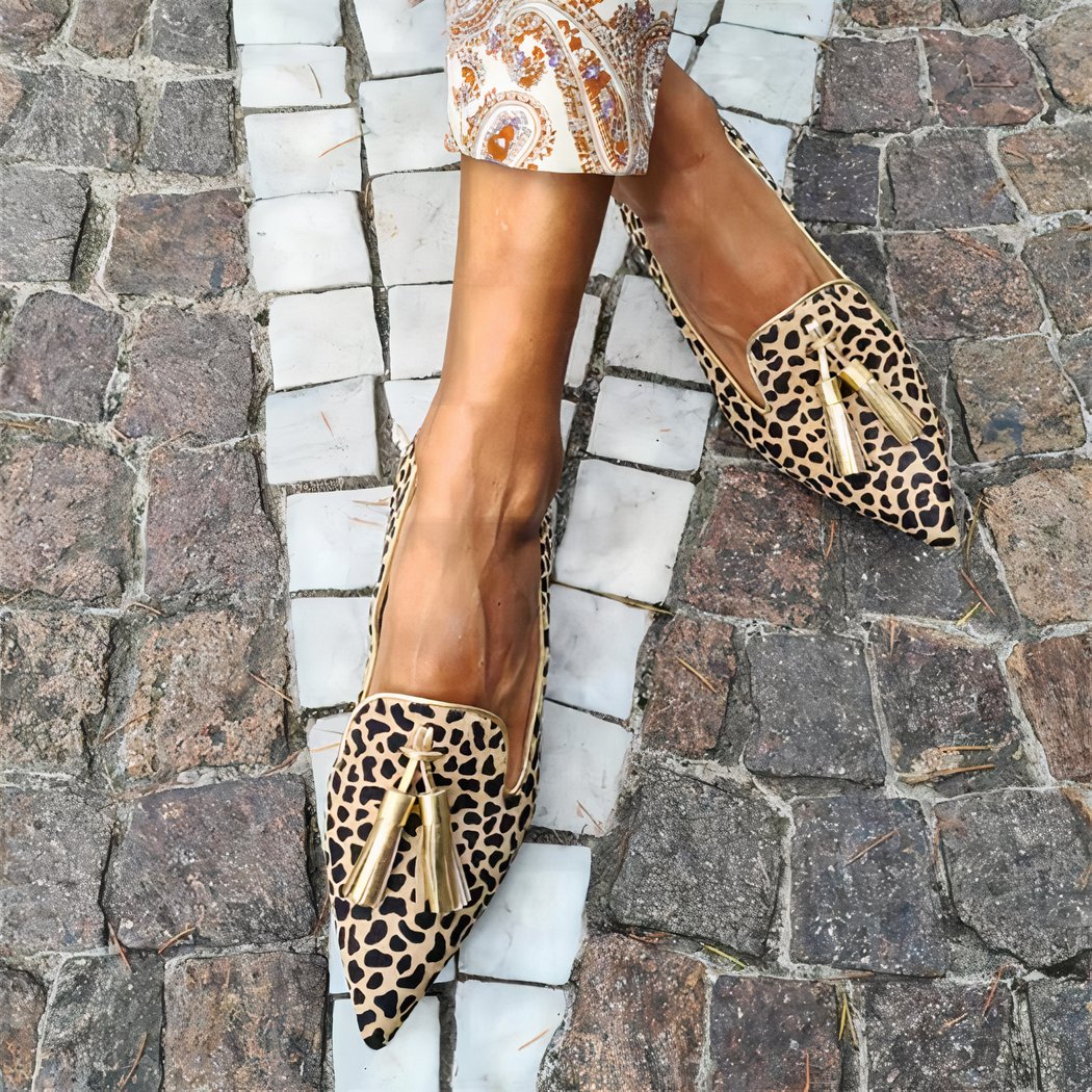 Woman in the street cross-legged wearing golden leopard pointed-toe loafers