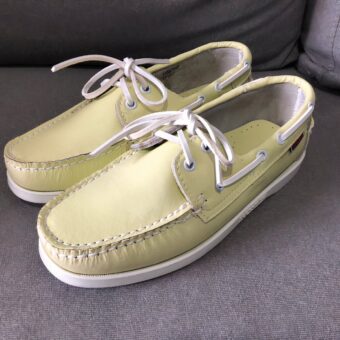 Pair of yellow lace-up boat moccasins on a grey floor