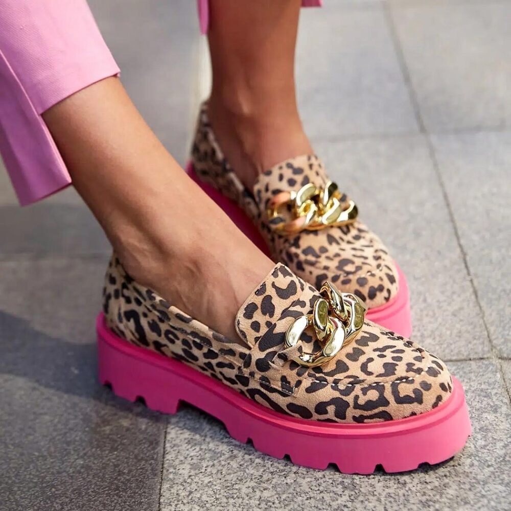 Foot of a woman wearing pink pants and leopard loafers with pink soles