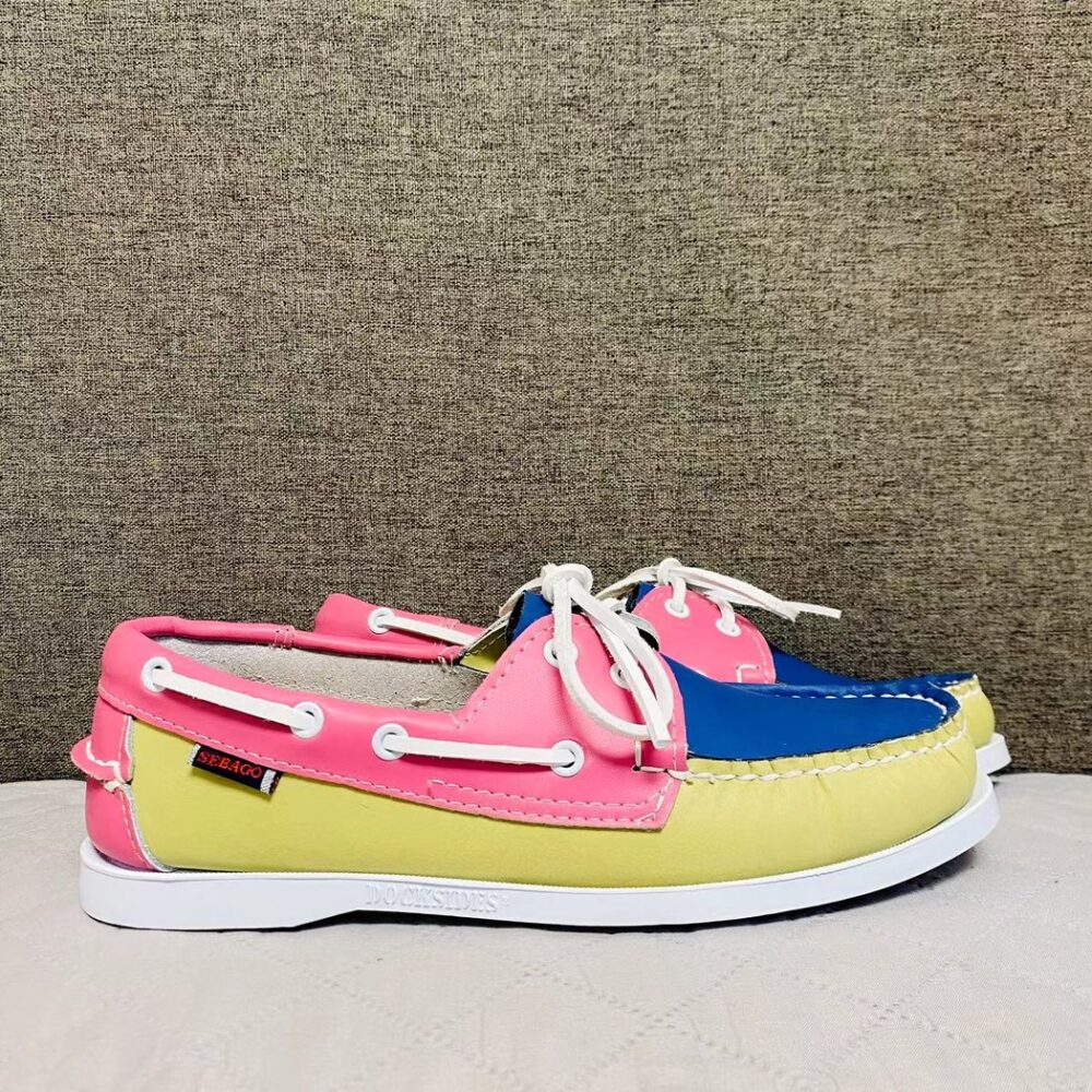 Yellow, pink and blue boat moccasins, placed in profile on a grey floor