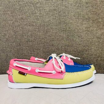 Yellow, pink and blue boat moccasins, placed in profile on a grey floor