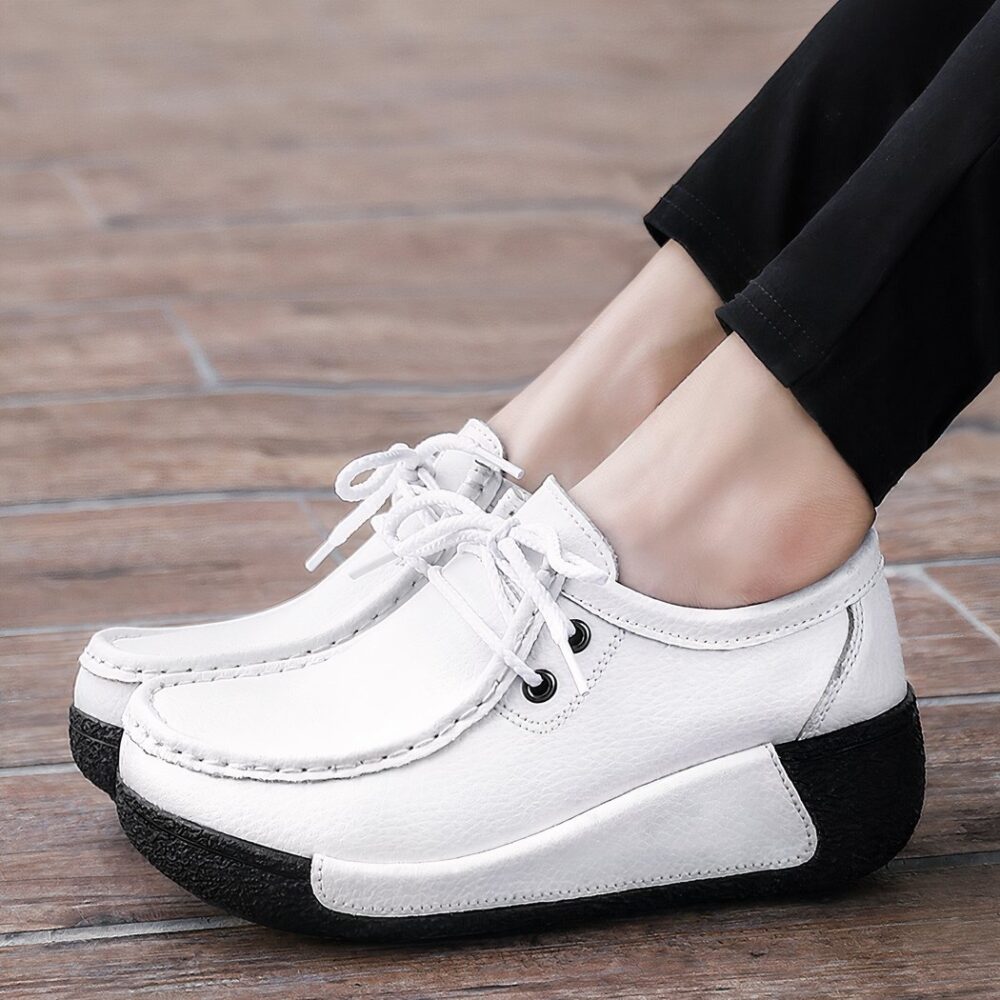 Woman in profile wearing black pants and white boat-style moccasins