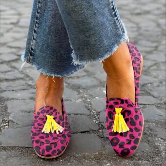 Woman standing cross-legged in the street wearing jeans and pink leopard print tassel loafers