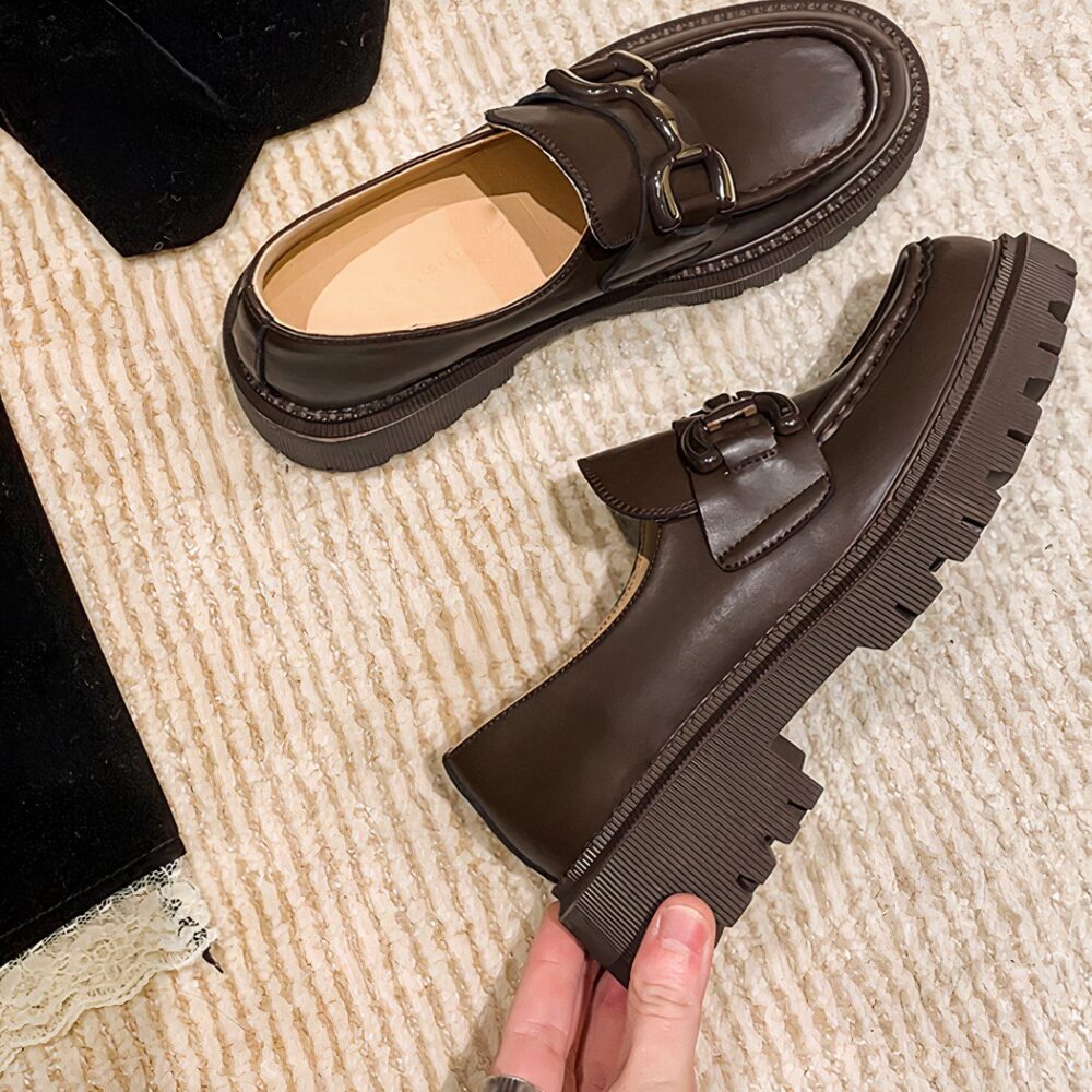 Two moccasins on a black beige tassel floor, one lying down