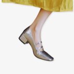 Silver-tone square-heeled ballerina loafer worn with a yellow dress on a white background