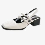 Single patent ballerina loafer with buckles and low heel on a white background