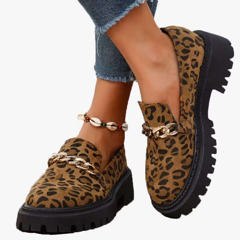 Leopard suede and chain loafers worn by a woman on a white background