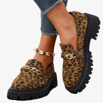 Leopard suede and chain loafers worn by a woman on a white background
