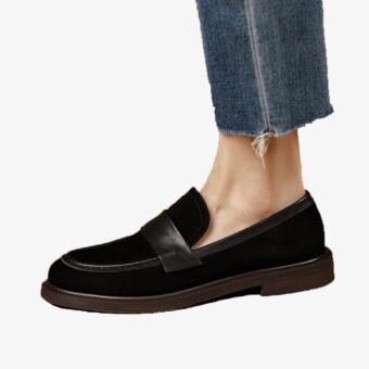 Elegant suede loafer for women worn with a pair of jeans on a white background